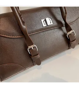 Close-up of brown leather handbag featuring silver metal twist lock and fine stitching