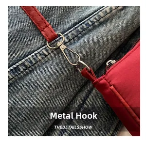 Detail view of red fabric baguette bag with silver lobster clasp hook and metal hardware