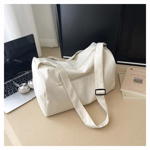 Close-up of a cream-colored cylindrical sports bag with a shoulder strap and modern design