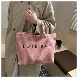 Detailed texture of pink corduroy tote bag with black embroidered TOTE BAG text