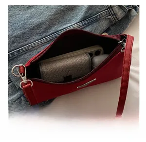 Detail showing red nylon shoulder bag interior with phone, wallet and earphones