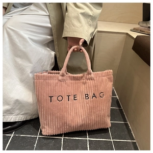 Detailed close-up of pink corduroy tote bag featuring thick TOTE BAG embroidery text