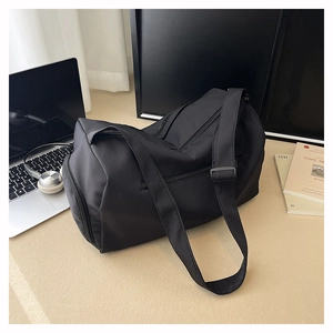 Detail of a large black nylon travel bag with shoe compartment and adjustable shoulder strap