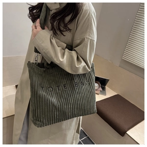 Détail d'un sac cabas en velours côtelé vert foncé avec broderie et rayures verticales