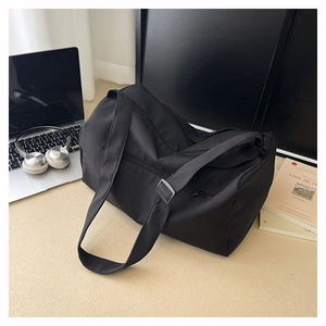 Macro view of a large black gym bag with adjustable straps and zipper pockets on a desk
