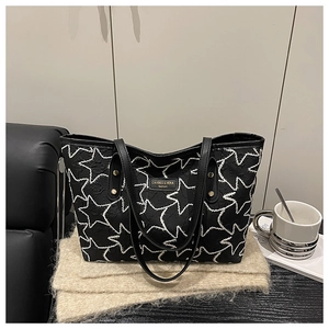 Detail of black quilted tote bag with white star pattern and stylish metal brand logo