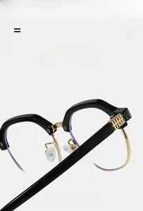 Detail of black and gold eyewear hinge showing intricate wavy metal decorative logo