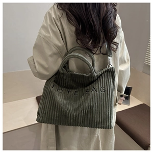 Detailed shot of an olive green corduroy tote bag with embroidered letters and strap