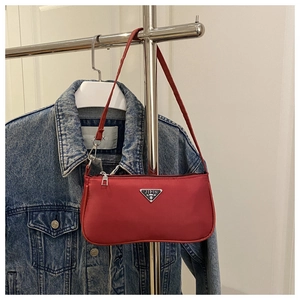 Macro detail of red nylon underarm bag with silver triangular metal logo and zipper