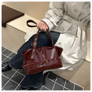 Detail van donkerrode laklederen shopper met metalen gesp en geplooide afwerking