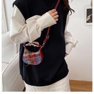 Detailed close-up of mini plaid crossbody bag with lace trim and red ribbon bows