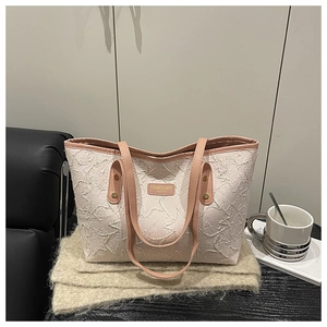 Close-up of pink star-patterned tote bag with leather straps on a soft blanket