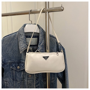 Close-up of a white nylon shoulder bag featuring a black triangular metal logo plate