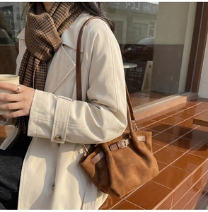 Close-up of brown suede bucket bag texture with retro buckle detail on a winter coat