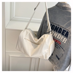 Close-up of white nylon pillow bag with side zipper pockets and wide shoulder strap