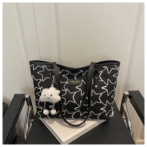 Detail of black quilted tote bag with white star embroidery and cloud plush charm