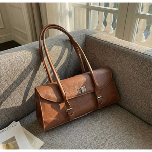 Close-up of brown vintage shoulder bag with silver twist lock on a soft sofa