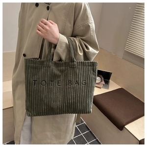 Gros plan du sac cabas en velours côtelé vert montrant la texture et la broderie