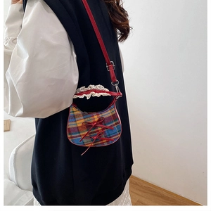 Detail of red and blue tartan shoulder bag with lace trim and ribbon bows on model