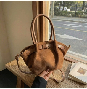 Detail of dark brown suede handbag with decorative buckle and soft matte texture