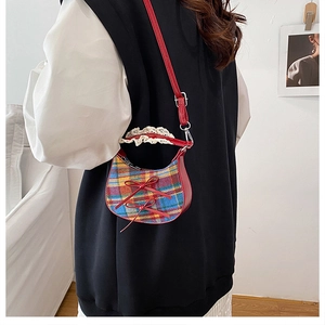 Detail of mini plaid crossbody bag with red bows and lace handle trim on model