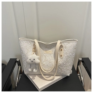 Detail of white star print tote bag with plush cloud charm on a pleated textured fabric