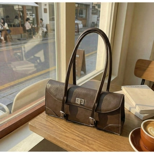 Close-up of vintage brown leather underarm bag with silver square twist lock on wooden table