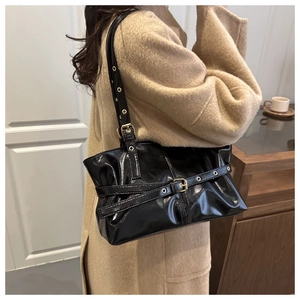 Detail of glossy black leather underarm bag with punk metal eyelets on chic beige coat