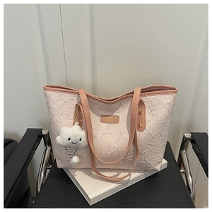 Detailed texture of pink star embossed tote bag with plush cloud charm on leather chair