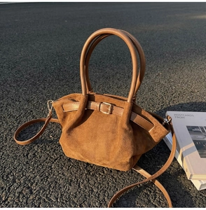 Detail of caramel suede tote bag with leather straps on outdoor asphalt surface