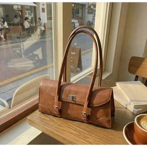 Detail of vintage brown leather baguette bag with silver buckles on a cafe table