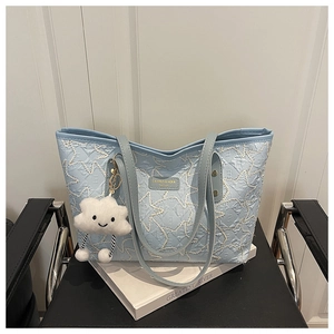Detail of light blue quilted tote bag with star stitching and plush cloud charm accessory