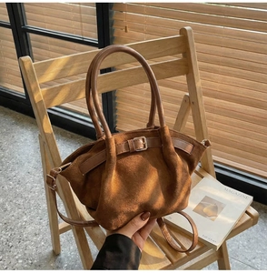 Detail of caramel suede crossbody bag with metal buckle on a wooden chair