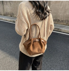 Detailed texture of brown suede crossbody bag with vintage metal buckle decoration