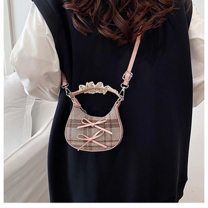 Detail of checkered crossbody bag with pink bows, lace handle, and leather straps