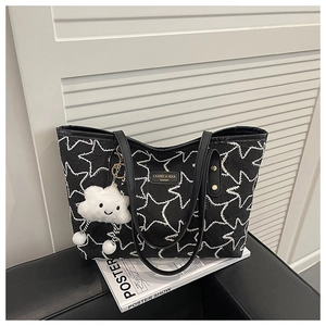 Close-up of black quilted tote bag with star embroidery and white cloud charm accessory