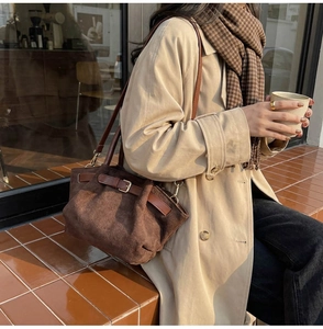 Detail of dark brown suede bucket bag with leather strap and pleated texture