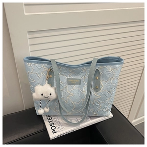 Close-up of light blue quilted tote bag with star embroidery and cloud plush pendant