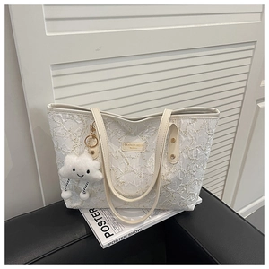 Close-up of beige quilted tote bag featuring metal logo and white cloud plush charm