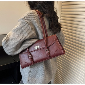 Detail view of burgundy underarm bag with silver buckle straps and metallic twist lock