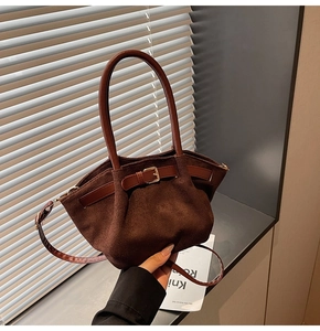 Detail of dark brown suede handbag featuring pleated texture and leather buckle accent