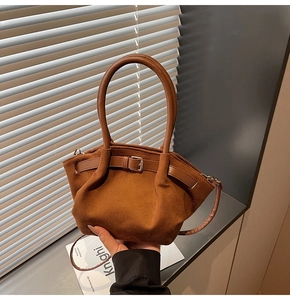 Detail of a brown suede handbag showing the adjustable buckle strap and stitching quality