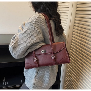 Detail of burgundy rectangular baguette bag with silver metallic buckle on model's shoulder