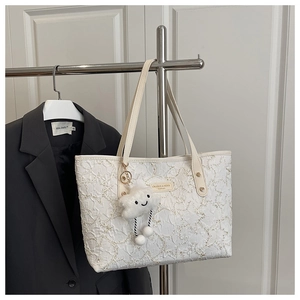 Detail of white textured tote bag with creamy leather strap and plush cloud charm