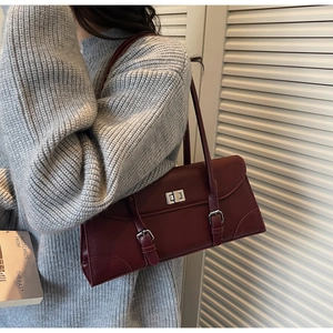 Detailed view of burgundy vintage shoulder bag with metal twist lock and decorative straps