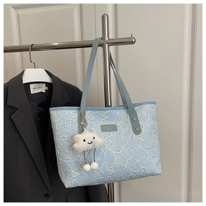 Detail of light blue quilted tote bag with star stitching and cloud pendant detail
