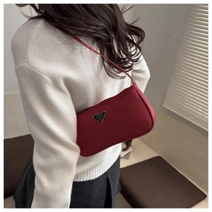 Detailed back view of a vibrant red nylon baguette bag worn over a beige sweater