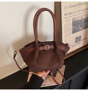 Detailed macro view of dark brown suede handbag with golden buckle and sleek leather strap