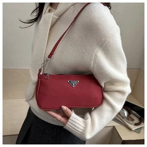 Close-up of red nylon underarm bag featuring silver triangular logo and fine fabric texture