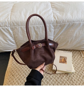 Detail of dark brown suede handbag featuring elegant leather belt strap and metal buckle
